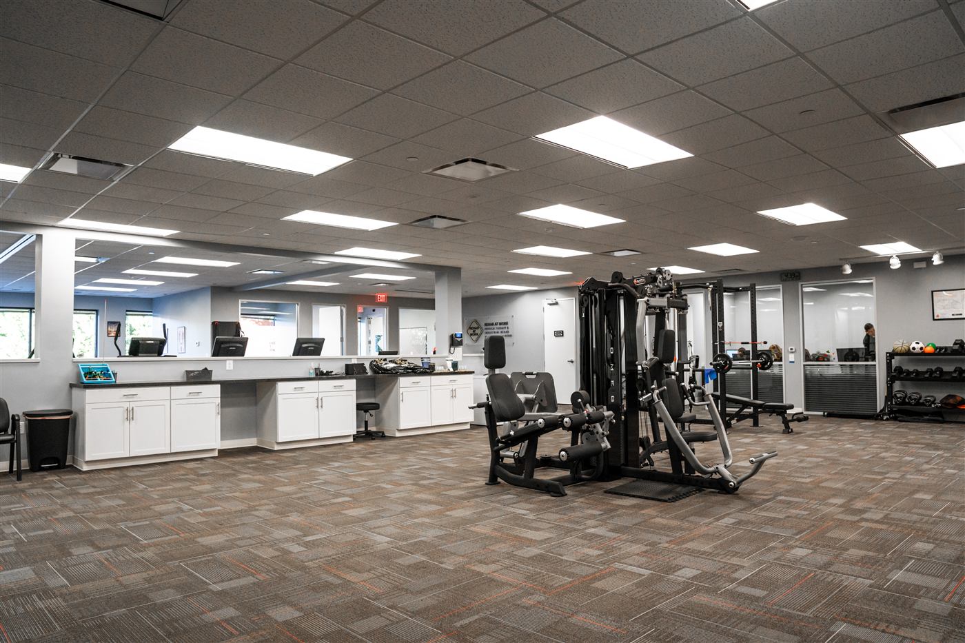 Strength and conditioning floor at the Herndon clinic with REHAB AT WORK wall signage
