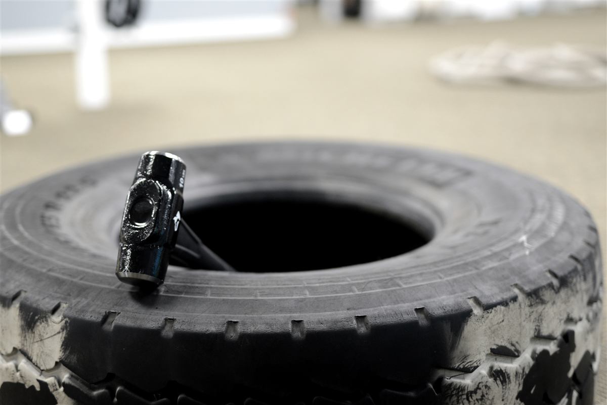 Sledgehammer resting on a truck tire in a work-simulation area