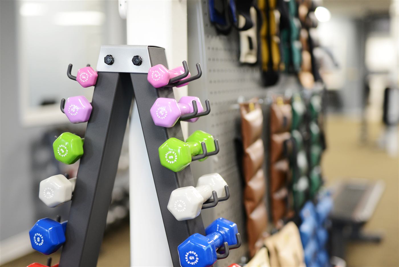 Dumbbell rack and weighted-vest wall in a clinic gym